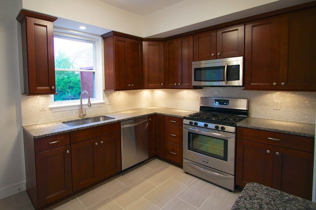 Kitchen remodel in Haymarket VA with dark wood cabinets, granite countertops, stainless steel appliances, and under cabinet lighting