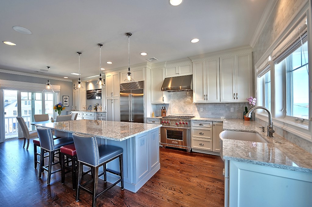 Bright Ashburn VA kitchen remodel with white cabinets, large island, stainless range, farmhouse sink, and hardwood floors