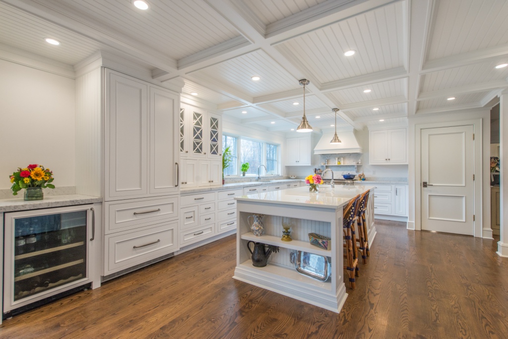 Great Falls VA kitchen remodel with white cabinets, coffered ceiling, center island, wine fridge, and hardwood floors
