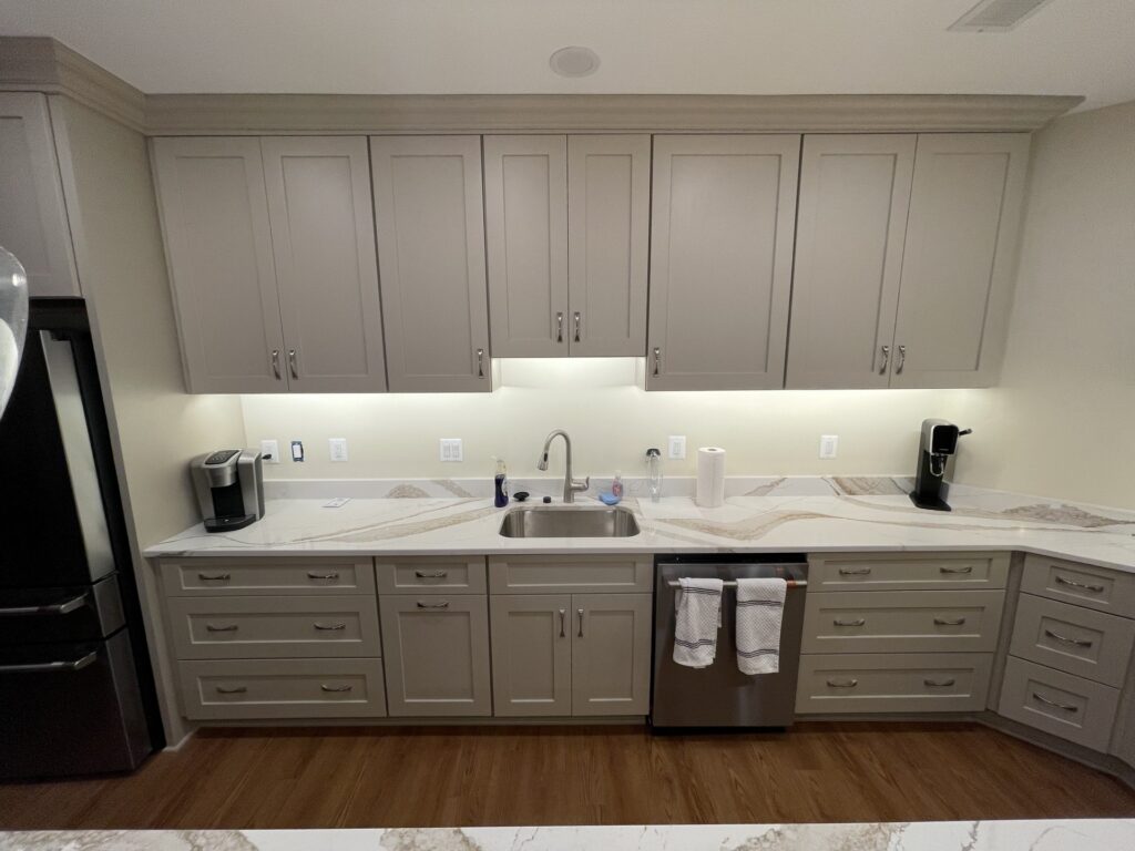 Custom sink wall cabinetry in McLean VA basement kitchen remodel with quartz countertops and under-cabinet lighting