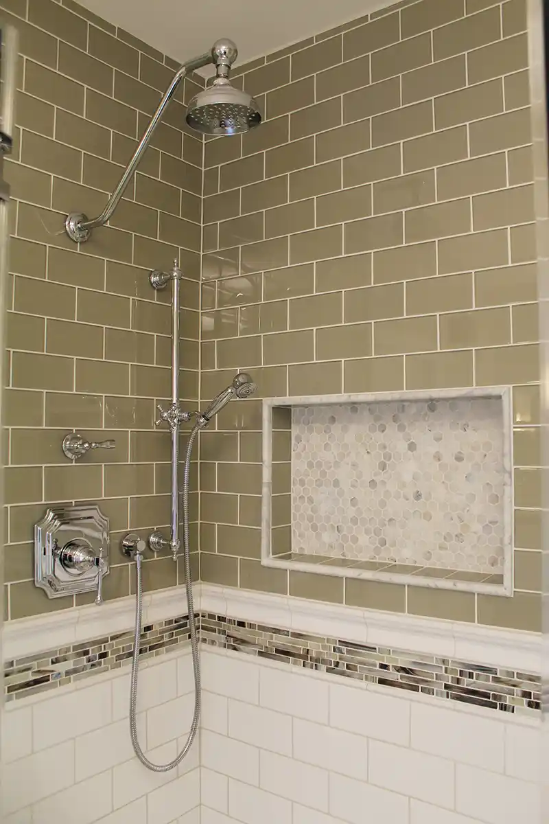 1930s Manassas VA bathroom remodel with taupe subway tile shower, marble hexagon niche, mosaic accent band, and chrome shower fixtures