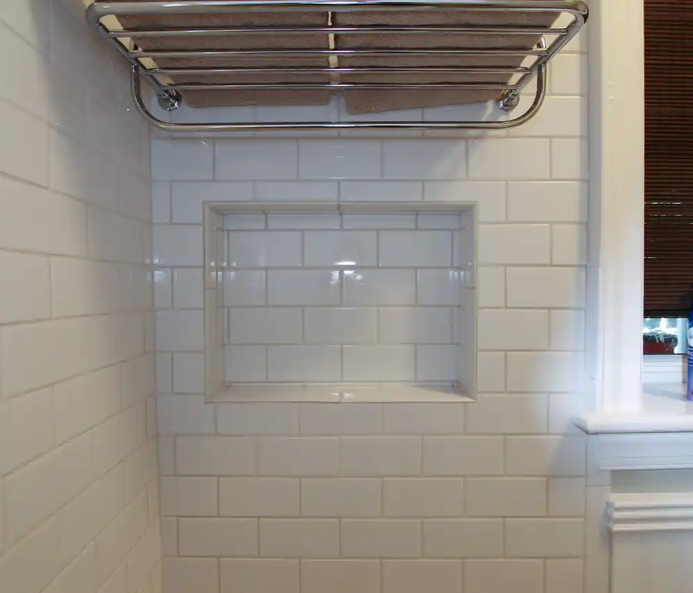 1930s Manassas VA hall bathroom remodel with white subway tile tub surround, recessed niche, chrome towel shelf, and classic trim