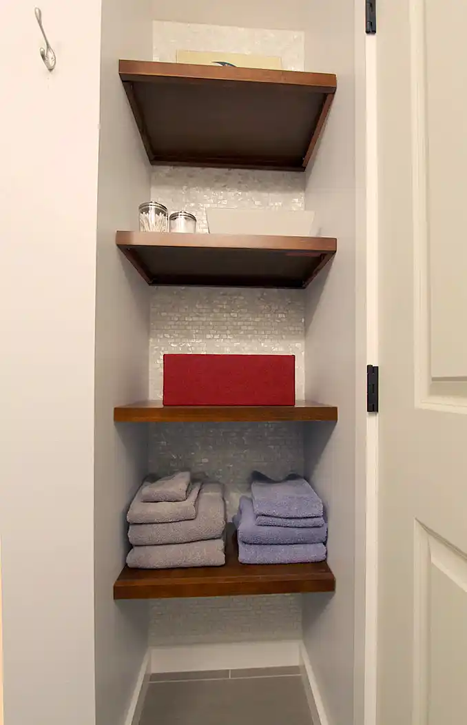 Gainesville VA bathroom remodel with built-in open shelving, wood shelves, pearl mosaic tile backing, and towel storage
