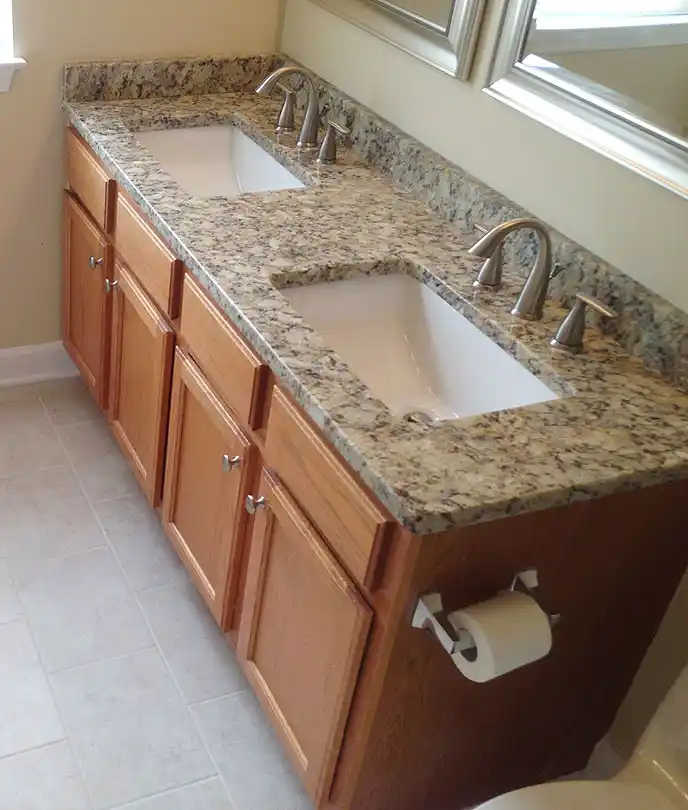 Gainesville VA bathroom remodel with wood double vanity, granite countertop, undermount sinks, brushed nickel faucets, and neutral floor tile