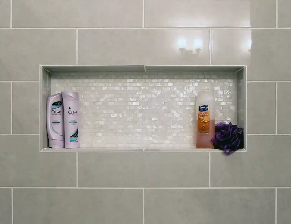 Gainesville VA bathroom remodel with gray tile shower niche, pearl mosaic accent tile, and built-in bath storage