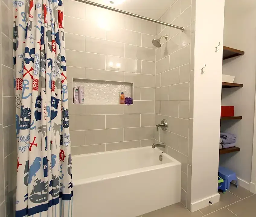Gainesville VA bathroom remodel with gray tile tub shower, recessed niche, brushed nickel fixtures, and built-in storage shelves