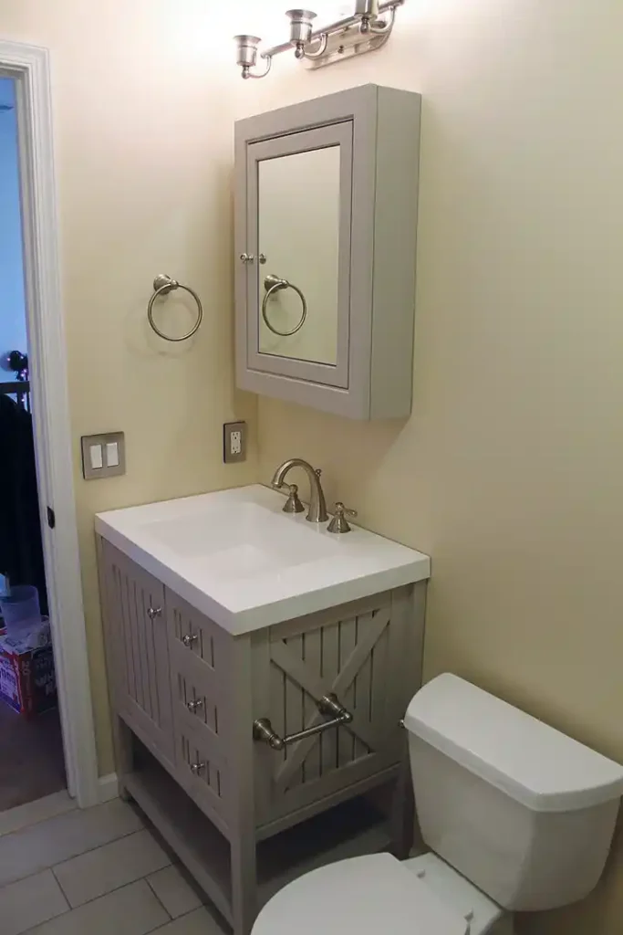 Gainesville VA bathroom remodel with gray vanity, white countertop, mirrored medicine cabinet, brushed nickel fixtures, and updated toilet
