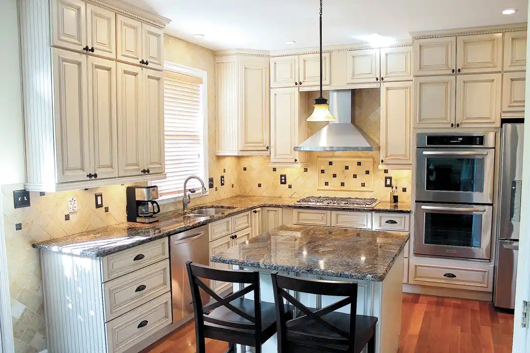 Gainesville VA kitchen remodel with cream cabinets, granite island, tile backsplash, stainless appliances, and built-in double oven