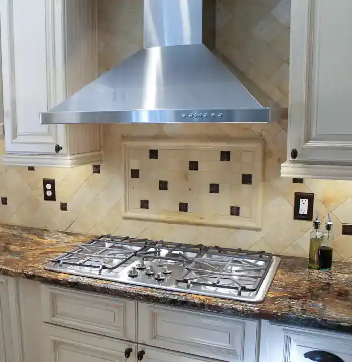 Gainesville VA kitchen remodel with gas cooktop, stainless range hood, cream cabinets, granite countertops, and decorative tile backsplash