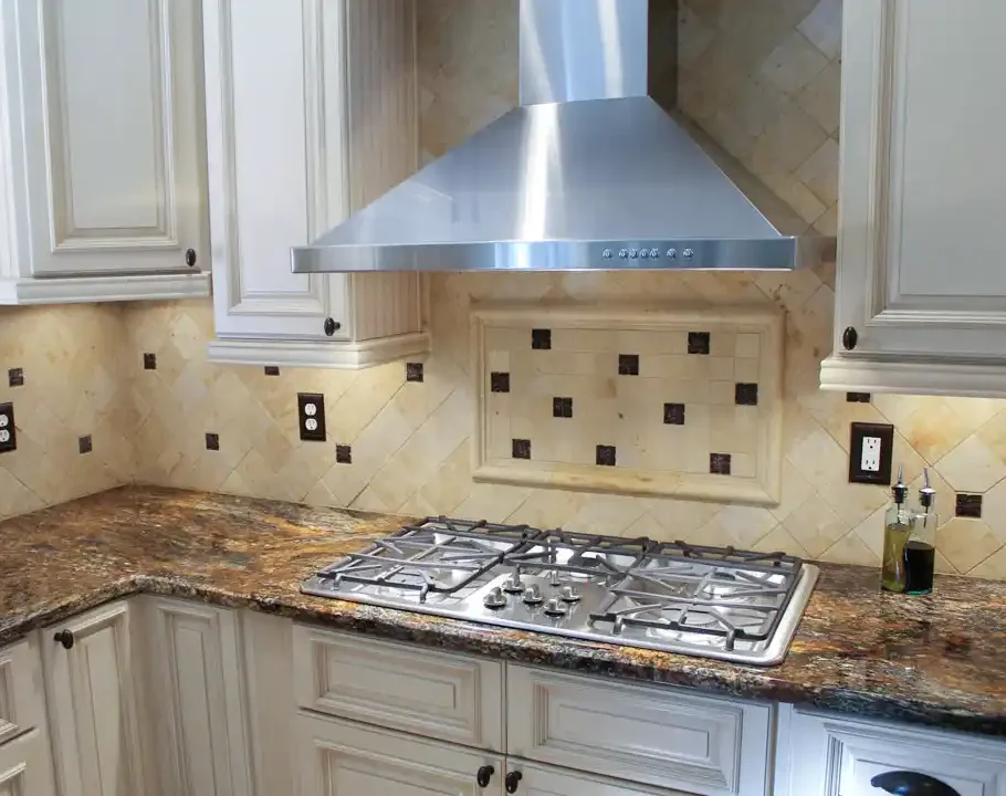 Gainesville VA kitchen remodel with gas cooktop, stainless range hood, cream cabinets, granite countertops, and decorative tile backsplash
