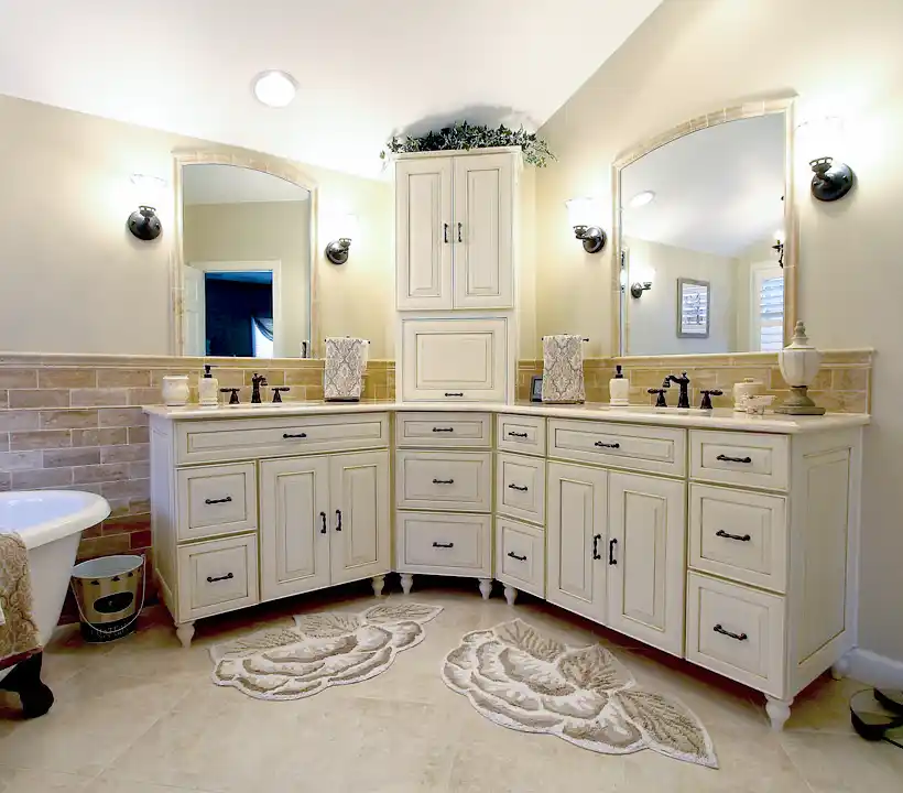 Gainesville VA primary bathroom remodel with corner double vanity, cream cabinetry, arched mirrors, freestanding tub, and tile wainscoting