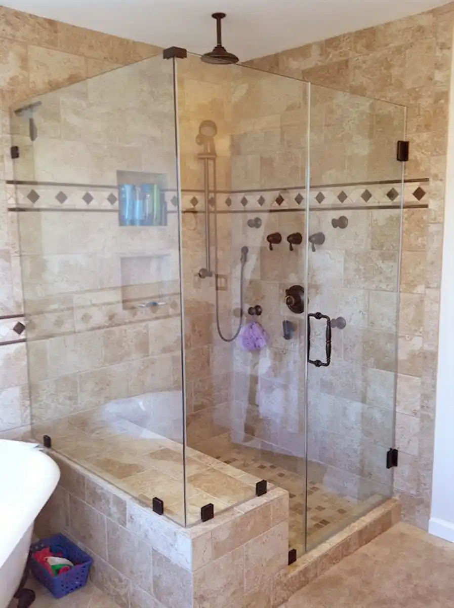 Gainesville VA primary bathroom remodel with glass walk-in tile shower, bench wall, recessed niches, decorative accent tile, and dark bronze fixtures
