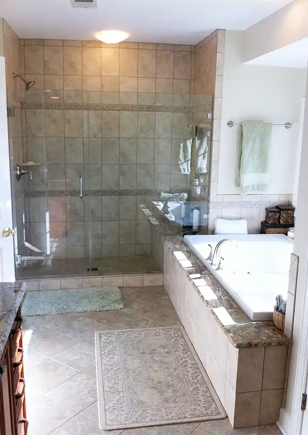 Haymarket VA primary bathroom remodel with glass-enclosed tile shower, jetted tub, granite tub deck, tile surround, and neutral floor tile