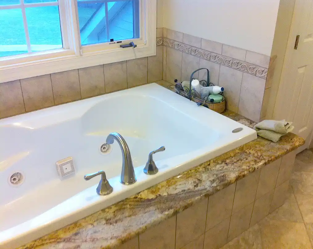 Haymarket VA primary bathroom remodel with jetted tub, granite tub deck, tile surround, brushed nickel fixtures, and decorative accent tile