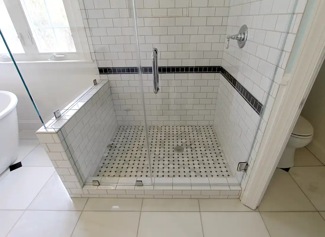 Manassas VA bathroom remodel with glass-enclosed white subway tile shower, black accent tile, and classic mosaic shower floor