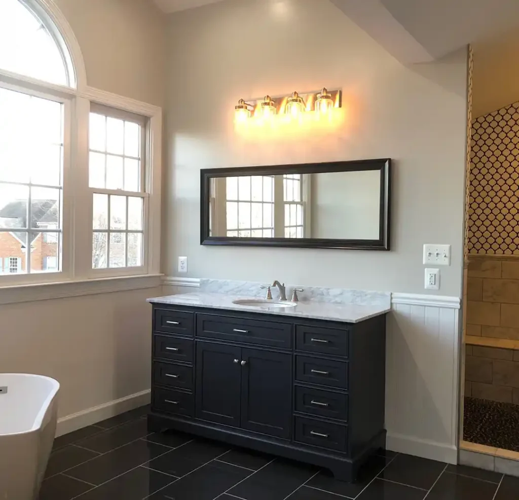 Manassas VA primary bathroom remodel with dark vanity, marble-look countertop, freestanding tub, tall windows, and patterned tile shower