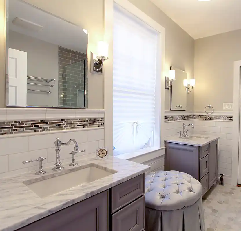 Manassas VA primary bathroom remodel with separate vanities, marble-look countertops, mosaic accent tile, and chrome fixtures