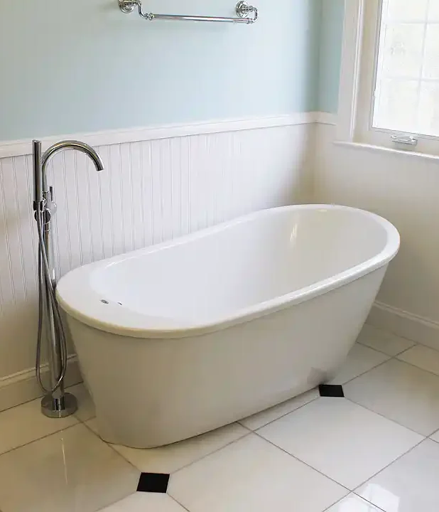 Manassas VA primary bathroom remodel with freestanding soaking tub, chrome tub filler, beadboard wainscoting, and marble-look floor tile