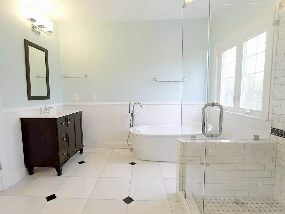 Manassas VA primary bathroom remodel with freestanding tub, glass-enclosed subway tile shower, dark vanity, and beadboard wainscoting