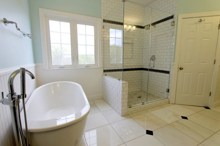 Manassas VA primary bathroom remodel with white subway tile shower, freestanding tub, and marble-look floor tile